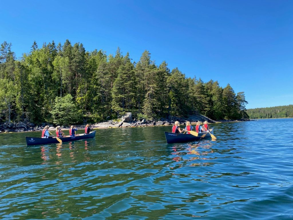 Sällskap paddlar roddbåt tillsammans i skärgården